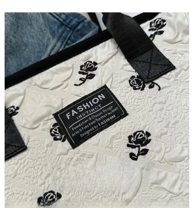 Détail du sac fourre-tout blanc plissé avec imprimé rose noire et anses tissées