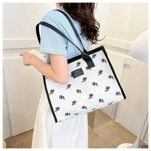 Sac fourre-tout matelassé blanc avec broderie de roses noires porté par un modèle