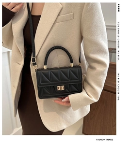 Detail of black quilted crossbody bag featuring a woven handle and golden metal twist lock