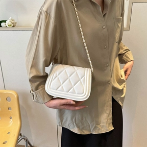 Detail of white quilted crossbody bag with golden chain strap and leather texture
