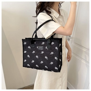Détail du sac cabas noir avec motif floral de roses blanches gaufrées et étiquette