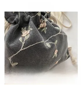 Detailed close-up of dark grey mesh fabric featuring pink floral embroidery and cotton drawstring