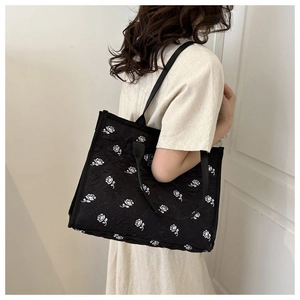 Détail du sac cabas en toile noire avec motif rose blanche et doubles bandoulières
