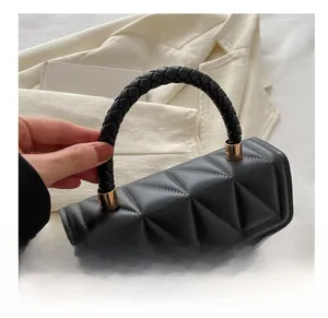 Detail of black quilted shoulder bag with woven leather handle and gold hardware