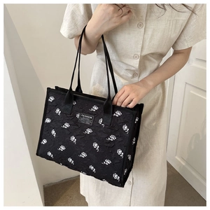 Gros plan détaillé sur le jacquard rose blanc du sac cabas noir en toile, vue latérale