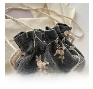Detail of grey mesh drawstring bag with delicate pink floral embroidery and cotton rope