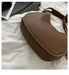 Close-up of the rounded base and stitching detail on the brown leather saddle bag