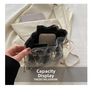 Detail showing capacity display of gray linen drawstring bag with pink floral embroidery
