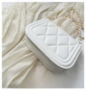 Detailed view of the white quilted crossbody bag with gold chain and refined bottom base
