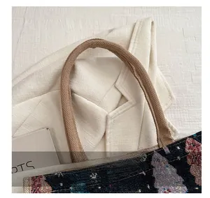 Détail des poignées en corde tressée marron renforcée sur un sac cabas en toile à motifs