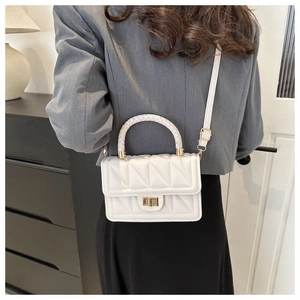 Model wearing a white quilted crossbody bag with woven handle and gold twist-lock closure