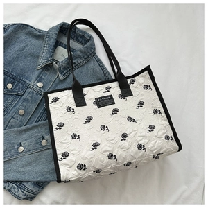 Vue détaillée du sac cabas en toile gaufrée avec motifs roses noires sur tissu blanc