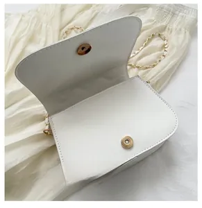 Detail view of white quilted crossbody bag with magnetic snap closure and chain strap