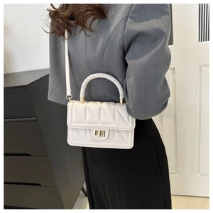 Detailed view of white quilted leather crossbody bag with gold hardware and woven handle