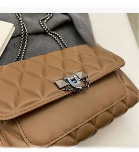 Detail of brown quilted leather bag with metallic rivet lock and silver chain strap