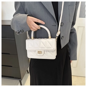 Detail of white quilted crossbody bag with woven handle and gold-tone turn-lock clasp