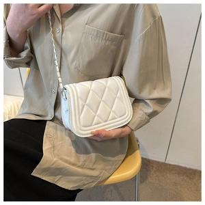 Detail of white quilted crossbody bag with gold metal and leather woven chain strap