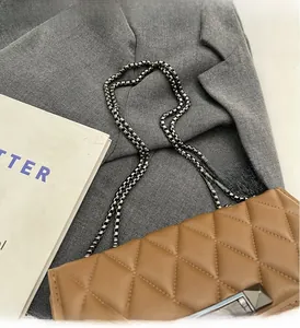 Detail of brown quilted faux leather texture with silver chain strap and metal lock