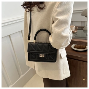 Close-up of quilted crossbody bag with gold twist lock and woven handle detail