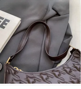 Detail of dark brown bag featuring star-embossed leather and golden metal hardware