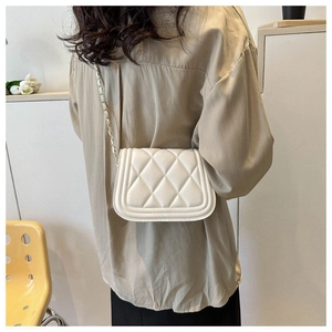 On-body view of a white quilted crossbody bag with gold chain strap and flap closure