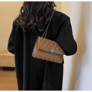 Brown quilted leather crossbody bag with silver clasp shown on a black blazer