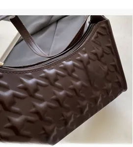 Detail of dark brown leather underarm bag with geometric star pattern embossing