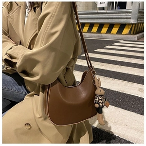 Detail of dark brown leather crescent saddle bag with a small bunny doll charm