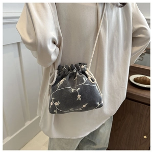 Detailed embroidery on a dark grey canvas bucket bag with floral patterns and drawstring