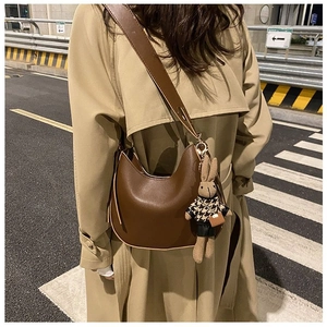 Detail of dark brown hobo bag with wide strap and cute rabbit plush charm