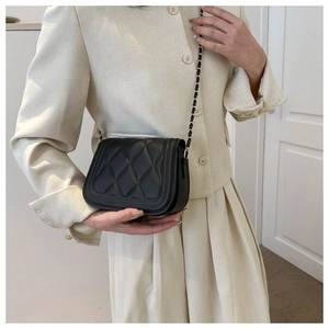 Detailed view of black quilted leather crossbody bag with elegant gold chain strap