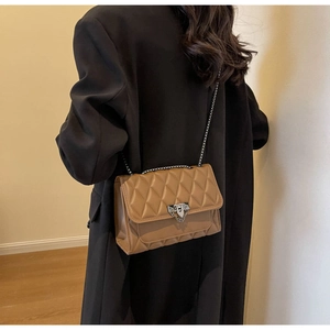 Detail of khaki quilted crossbody bag with silver chain strap on black blazer model