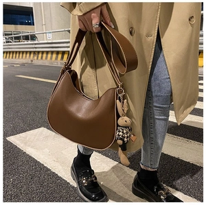 Outdoor street shot of brown leather hobo saddle bag with a cute plush rabbit charm
