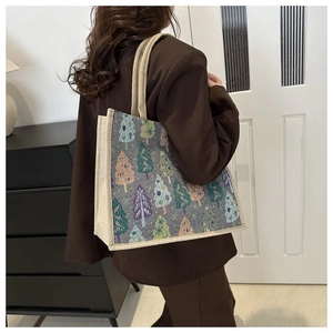 Détail d'un sac cabas en jacquard gris avec motifs de forêt colorés dans un décor intérieur