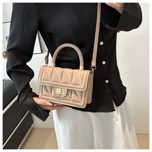 Detail of beige quilted mini crossbody bag featuring a golden metal twist lock closure