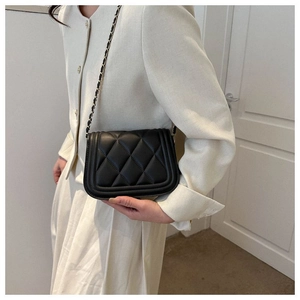 Close-up of black quilted PU leather crossbody bag with metal chain strap on model