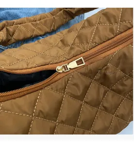 Detail of smooth gold zipper and quilted nylon pattern on brown crossbody bag