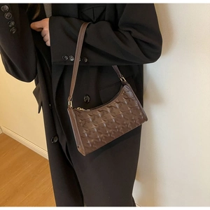 Detail of dark brown underarm bag featuring star pattern embossing and gold zipper