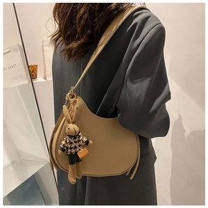 Detail of tan crescent saddle bag with cute rabbit charm showing shoulder strap fit