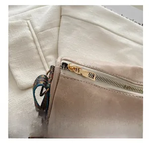 Detail eines glatten Metallreißverschlusses an einer beigen Tasche mit Muster-Gurt