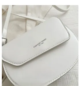 Detail of white saddle bag with FASHION TREND EST 1996 text and crossbody strap