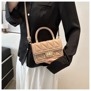 Detail of beige quilted crossbody bag with golden metal lock and textured handle
