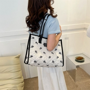 Sac cabas en toile blanc avec imprimé rose noire et texture plissée porté à l'épaule du mannequin