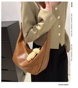 Brown litchi leather hobo bag with a plush bear charm on a comfortable wide strap