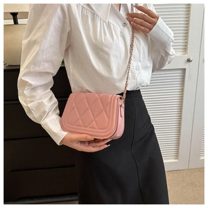 Detail of pink quilted flap bag with gold chain strap on a white shirt background