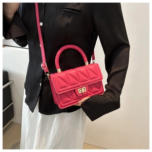 Detailed view of rose red quilted crossbody bag with woven handle and gold twist lock