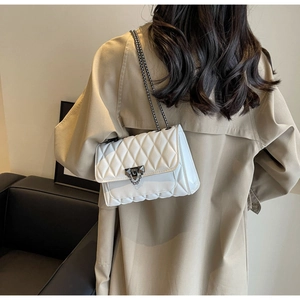 Detail of white quilted crossbody bag with gunmetal chain strap and metal lock