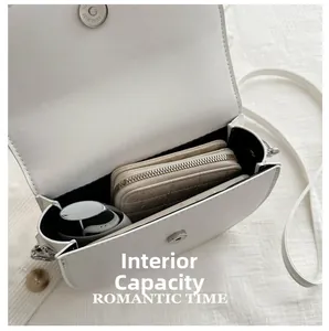 Internal capacity view of white saddle bag showing leather texture and magnetic buckle