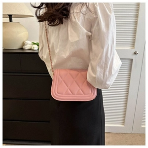 Detailed view of pink quilted faux leather crossbody bag with golden chain strap on cabinet