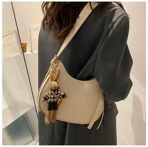 Close-up of creamy white half-moon saddle bag featuring a cute bunny plush charm